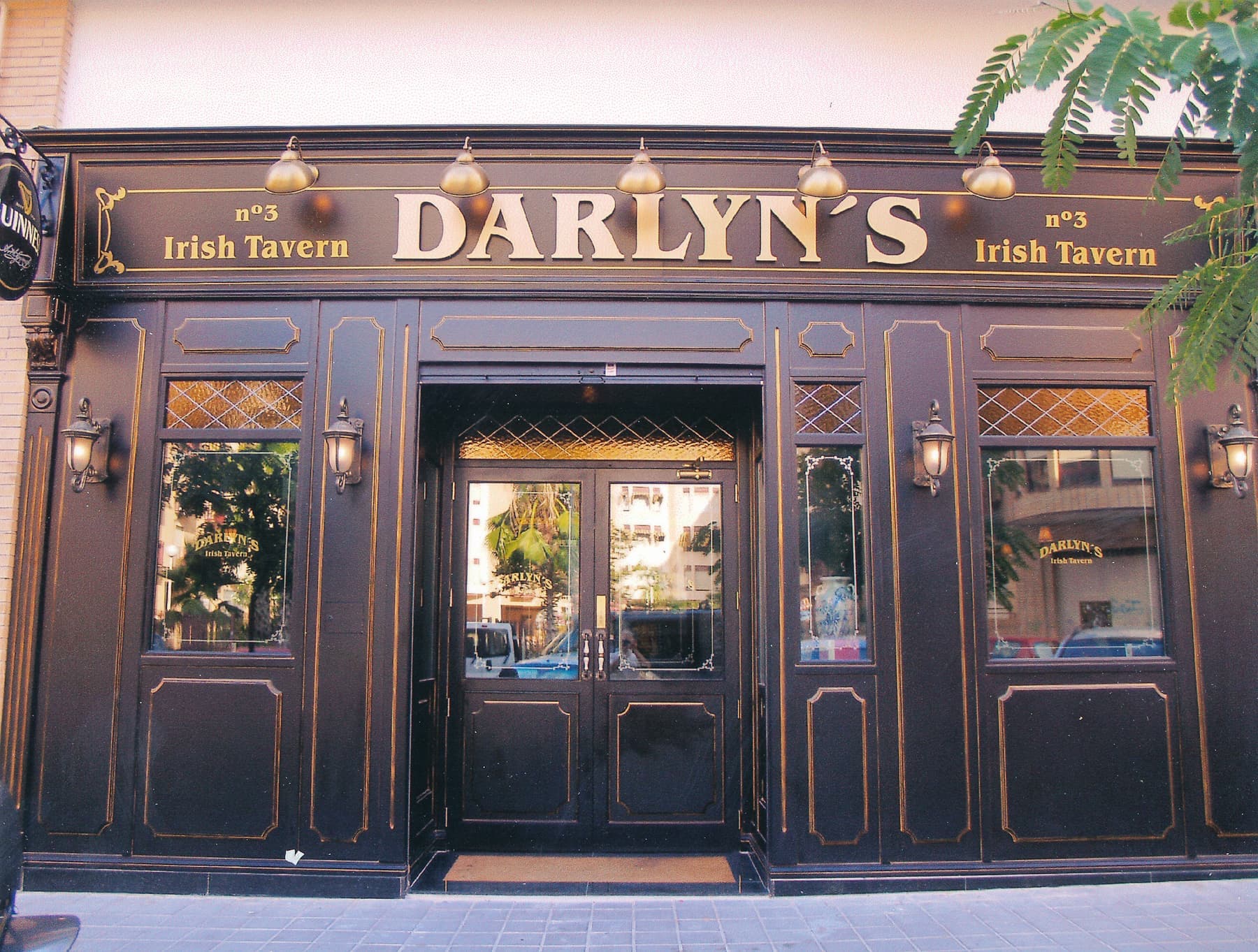 Fachada de madera de la taberna Darlyn's con letras doradas y apliques de luz