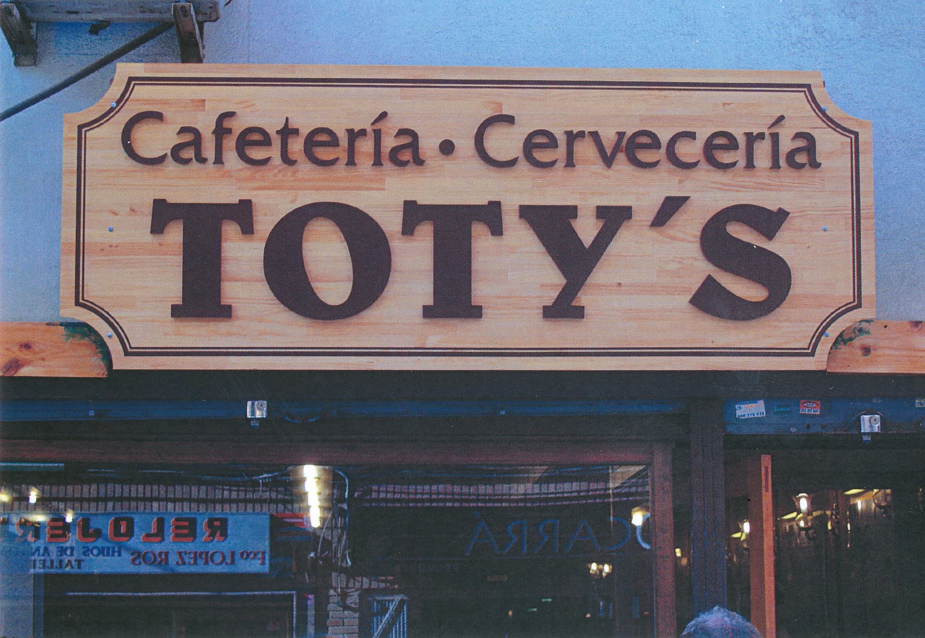 Rótulo de madera tallada de la cafetería cervecería Toty's iluminado de noche
